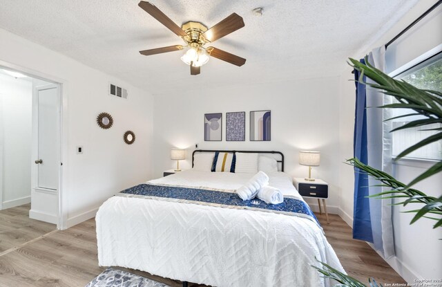 16414 Spruce Cove St, San Antonio, TX 78247 - bedroom with light wood finished floors, baseboards, ceiling fan, and a textured ceiling