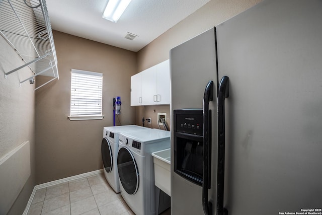 5018 Ashton Audrey, San Antonio, TX 78249 - laundry area featuring independent washer and dryer, cabinet space, baseboards, and light tile patterned flooring