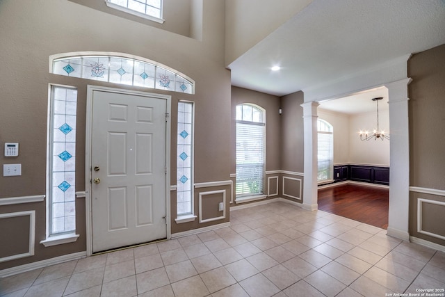 5018 Ashton Audrey, San Antonio, TX 78249 - tiled foyer entrance with a chandelier, ornate columns, plenty of natural light, a wainscoted wall, and a decorative wall