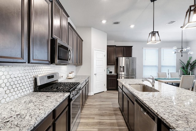 2423 Olive Way, San Antonio, TX 78259 - kitchen featuring stainless steel appliances, a sink, dark brown cabinetry, light stone counters, and recessed lighting