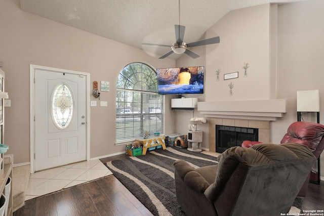 6283 Valley Bay, San Antonio, TX 78250 - foyer entrance with vaulted ceiling, a ceiling fan, a tiled fireplace, light wood-style flooring, and a textured ceiling