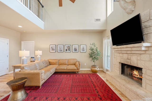 102 Kendall View Dr, Boerne, TX 78006 - living room with a high ceiling, a stone fireplace, wood finished floors, baseboards, and a ceiling fan