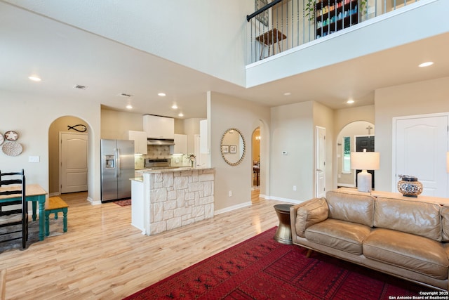 102 Kendall View Dr, Boerne, TX 78006 - living room featuring arched walkways, light wood-style floors, recessed lighting, baseboards, and a high ceiling