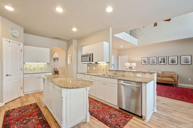 102 Kendall View Dr, Boerne, TX 78006 - kitchen with stainless steel appliances, a sink, light wood-type flooring, open floor plan, and arched walkways