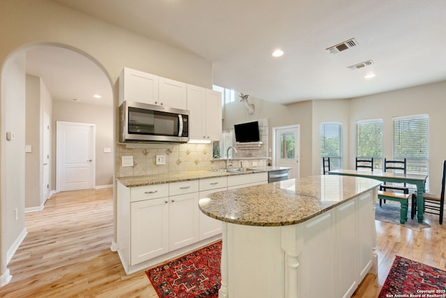 102 Kendall View Dr, Boerne, TX 78006 - kitchen with appliances with stainless steel finishes, a sink, light wood-type flooring, arched walkways, and recessed lighting