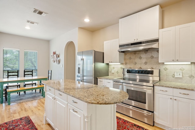 102 Kendall View Dr, Boerne, TX 78006 - kitchen featuring under cabinet range hood, stainless steel appliances, light wood-style floors, arched walkways, and a center island
