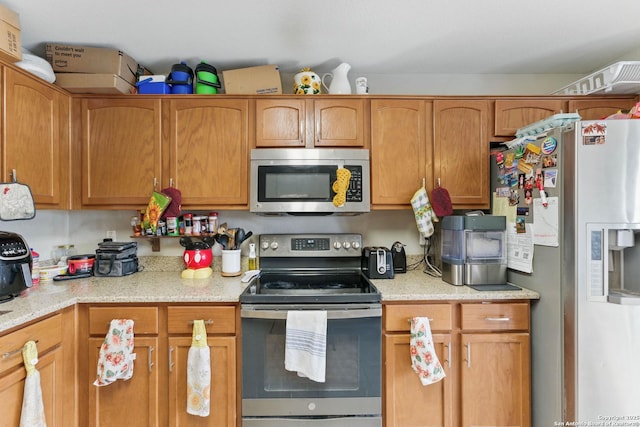 10715 Black Wolf Bay, San Antonio, TX 78245 - kitchen featuring appliances with stainless steel finishes, brown cabinetry, and light stone countertops