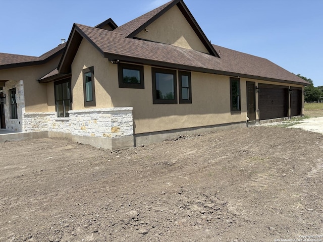 811 Horseshoe Fls, Bandera, TX 78003 - view of home's exterior featuring stucco siding, a shingled roof, a garage, and stone siding