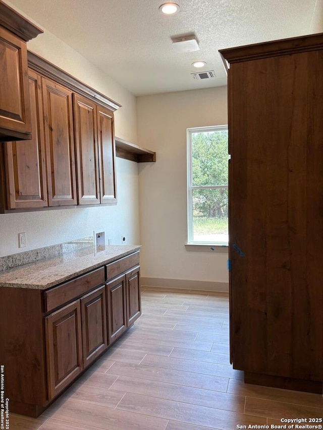 811 Horseshoe Fls, Bandera, TX 78003 - kitchen featuring light wood-style flooring, baseboards, a textured ceiling, light stone countertops, and recessed lighting