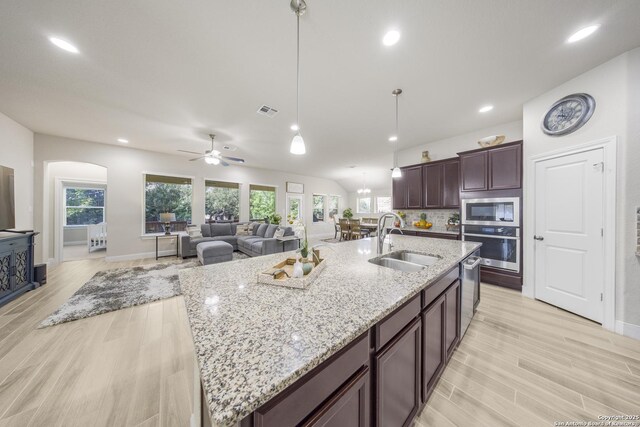 12322 Saddle Up Dr, San Antonio, TX 78254 - kitchen with stainless steel appliances, a sink, light wood finished floors, baseboards, and a center island with sink