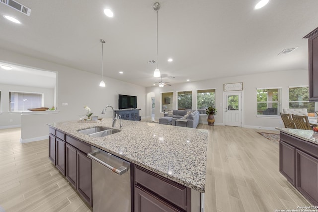 12322 Saddle Up Dr, San Antonio, TX 78254 - kitchen featuring dishwasher, a sink, baseboards, open floor plan, and light wood-style flooring