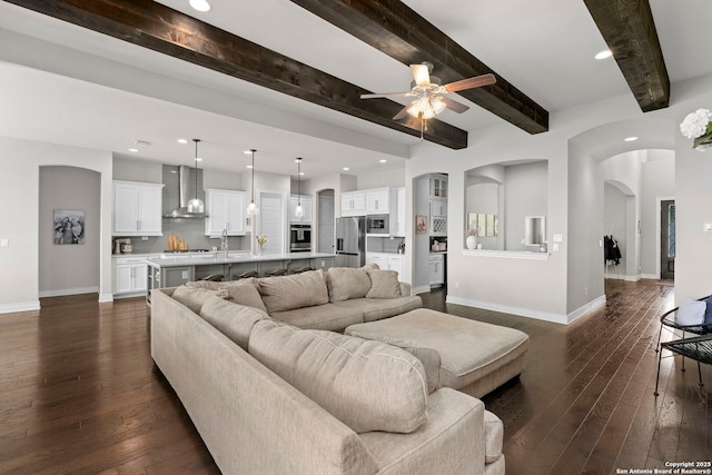 3130 Running Fawn, San Antonio, TX 78261 - living area with ceiling fan, dark wood-style floors, baseboards, beam ceiling, and arched walkways