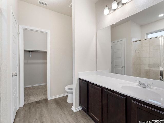 10518 Green Rock, San Antonio, TX 78223 - full bath featuring wood finished floors, toilet, a shower stall, vanity, and a walk in closet