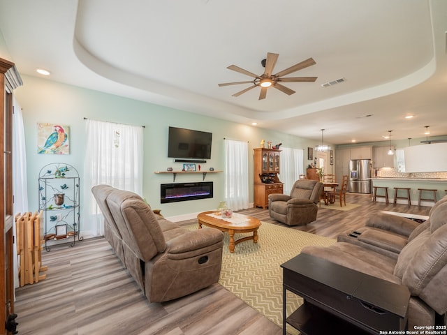 2872 Lakeview Dr, Canyon Lake, TX 78133 - living area with a tray ceiling, light wood-type flooring, ceiling fan, recessed lighting, and a glass covered fireplace