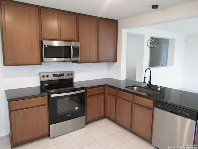 8517 Barefoot Ln, Converse, TX 78109 - kitchen featuring appliances with stainless steel finishes, a sink, dark stone counters, light tile patterned floors, and decorative backsplash