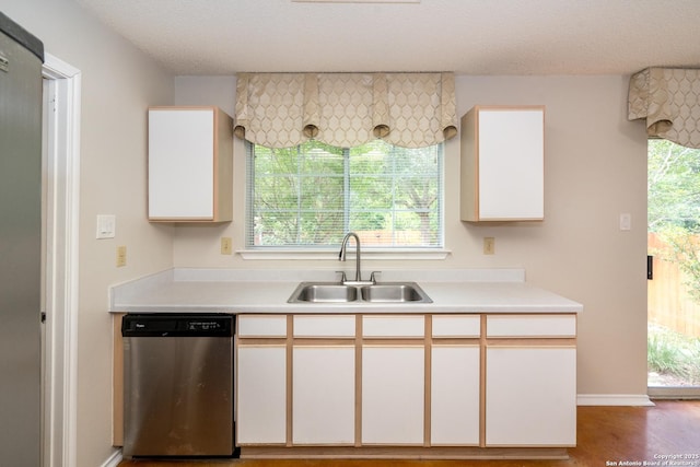 5731 Bypass Trl, San Antonio, TX 78244 - kitchen with stainless steel dishwasher, a sink, light countertops, white cabinets, and a textured ceiling