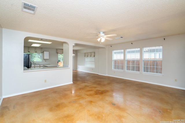 5731 Bypass Trl, San Antonio, TX 78244 - unfurnished living room with ceiling fan, arched walkways, concrete flooring, a textured ceiling, and baseboards