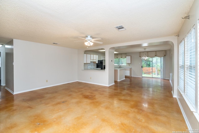 5731 Bypass Trl, San Antonio, TX 78244 - unfurnished living room with concrete flooring, ceiling fan, a textured ceiling, arched walkways, and a sink