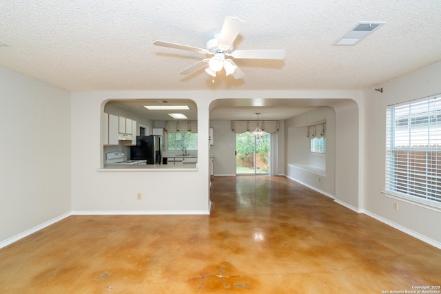 5731 Bypass Trl, San Antonio, TX 78244 - unfurnished living room featuring concrete floors, a chandelier, a textured ceiling, arched walkways, and a ceiling fan