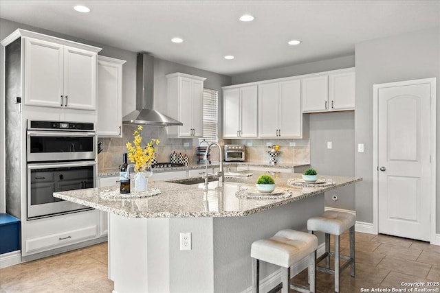 10218 Nate Range, San Antonio, TX 78254 - kitchen featuring wall chimney exhaust hood, double oven, white cabinets, recessed lighting, and backsplash