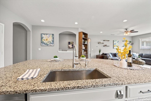 10218 Nate Range, San Antonio, TX 78254 - kitchen with a sink, open floor plan, light stone countertops, a ceiling fan, and recessed lighting