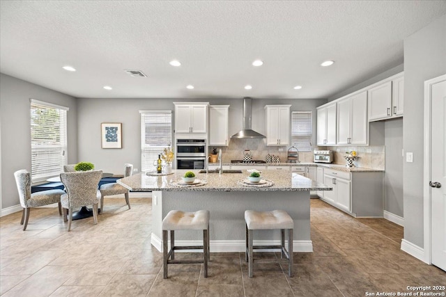 10218 Nate Range, San Antonio, TX 78254 - kitchen featuring wall chimney exhaust hood, stainless steel appliances, a sink, backsplash, and white cabinets