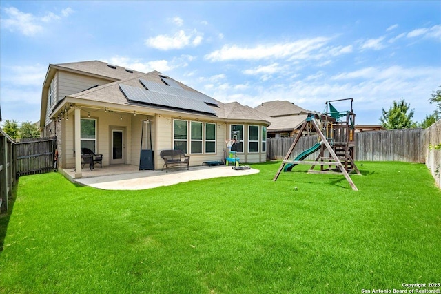 10218 Nate Range, San Antonio, TX 78254 - rear view of house with roof mounted solar panels, a playground, a patio area, and a shingled roof