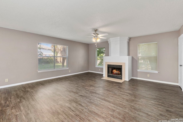 8131 Talkenhorn, Converse, TX 78109 - unfurnished living room with ceiling fan, a textured ceiling, dark wood-style floors, a tile fireplace, and baseboards