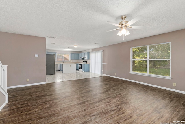 8131 Talkenhorn, Converse, TX 78109 - unfurnished living room featuring a textured ceiling, light wood-type flooring, a ceiling fan, and baseboards