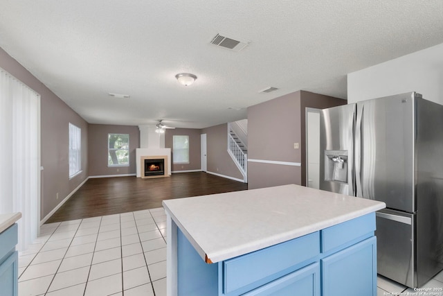 8131 Talkenhorn, Converse, TX 78109 - kitchen with stainless steel fridge with ice dispenser, a ceiling fan, blue cabinetry, light countertops, and a textured ceiling