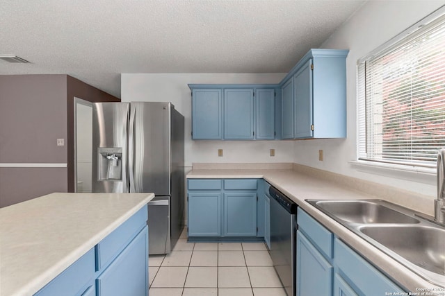8131 Talkenhorn, Converse, TX 78109 - kitchen featuring appliances with stainless steel finishes, a textured ceiling, blue cabinets, a sink, and light tile patterned floors