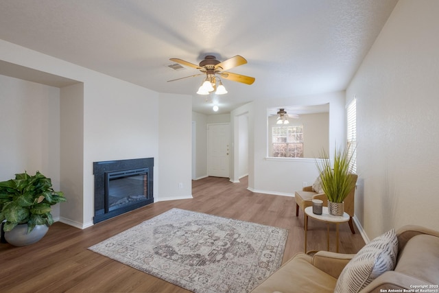 135 Agency Oaks, San Antonio, TX 78249 - living room featuring wood finished floors, a ceiling fan, a glass covered fireplace, and baseboards