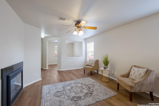135 Agency Oaks, San Antonio, TX 78249 - living area with wood finished floors, ceiling fan, a glass covered fireplace, and baseboards