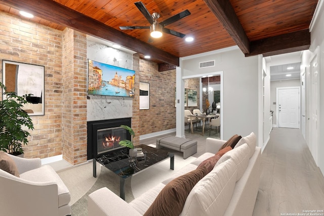 1170 Garraty Rd Unit 14, San Antonio, TX 78209 - living area with wooden ceiling with exposed beams, brick wall, baseboards, a ceiling fan, and a brick fireplace