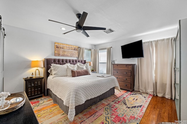 221 Calumet, San Antonio, TX 78209 - bedroom with light wood-style floors, ceiling fan, a barn door, and recessed lighting