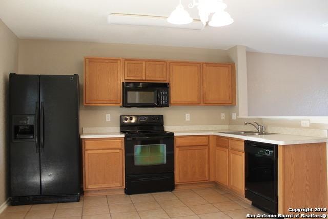 10047 Powderhouse Dr, San Antonio, TX 78239 - kitchen with black appliances, light countertops, a sink, and light tile patterned floors