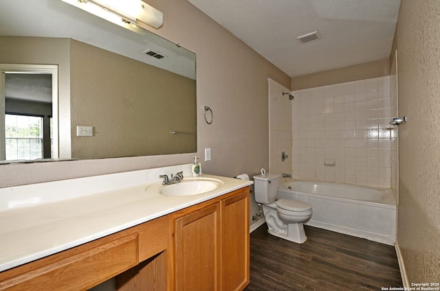 10047 Powderhouse Dr, San Antonio, TX 78239 - bathroom with toilet, wood finished floors, vanity, a textured wall, and shower / washtub combination