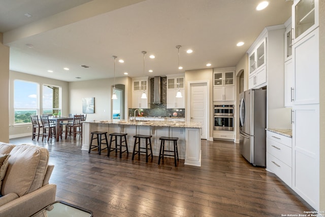 3122 Running Fawn, San Antonio, TX 78261 - kitchen featuring stainless steel appliances, wall chimney exhaust hood, open floor plan, dark wood-style floors, and a large island