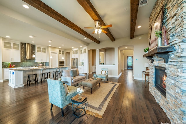 3122 Running Fawn, San Antonio, TX 78261 - living room with arched walkways, dark wood finished floors, ceiling fan, beamed ceiling, and a fireplace