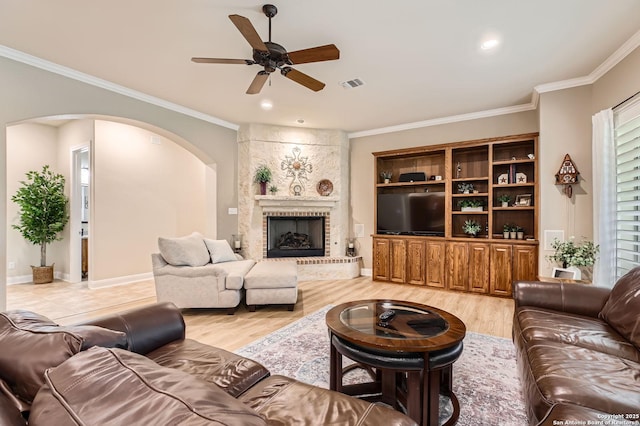 12424 Andice, Helotes, TX 78023 - living room with arched walkways, a ceiling fan, ornamental molding, light wood-style flooring, and a fireplace