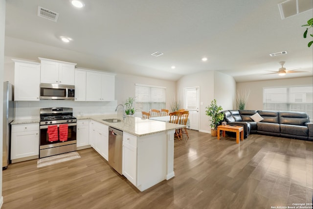6022 Akin Pl, San Antonio, TX 78261 - kitchen featuring stainless steel appliances, a sink, a peninsula, open floor plan, and white cabinets