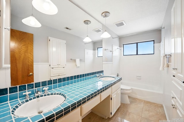 19739 Encino Way, San Antonio, TX 78259 - bathroom with toilet, double vanity, bathing tub / shower combination, tile patterned floors, and wainscoting