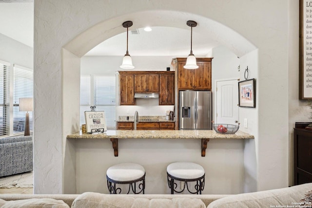 2756 Indian Wls, Kerrville, TX 78028 - kitchen with stainless steel refrigerator with ice dispenser, arched walkways, under cabinet range hood, a kitchen breakfast bar, and a textured wall