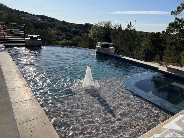 239 Damar Cv, Canyon Lake, TX 78133 - view of swimming pool with a wooded view and a pool with connected hot tub