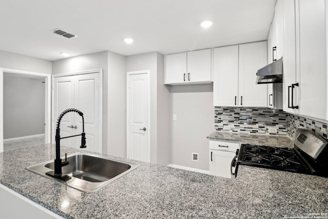 4526 Meadowland, San Antonio, TX 78222 - kitchen with stainless steel gas range oven, under cabinet range hood, a sink, white cabinets, and tasteful backsplash