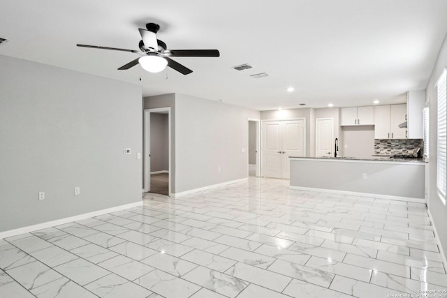 4526 Meadowland, San Antonio, TX 78222 - unfurnished living room featuring a ceiling fan, recessed lighting, a sink, baseboards, and light marble finish floors