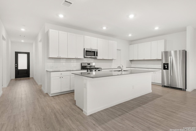 31908 Native Sun, Bulverde, TX 78163 - kitchen with stainless steel appliances, decorative backsplash, a sink, light wood-type flooring, and an island with sink