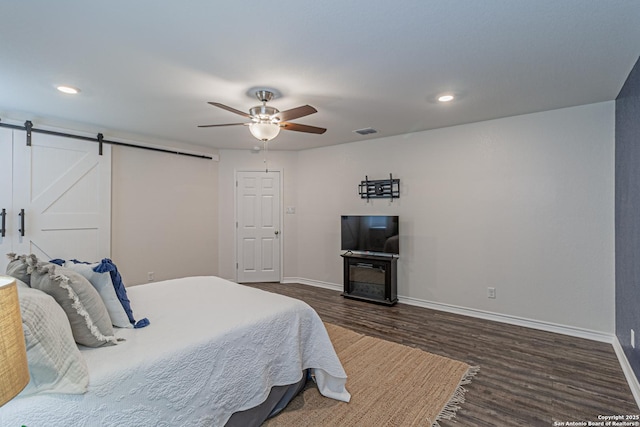 15166 Orpheus Way, San Antonio, TX 78245 - bedroom with dark wood-type flooring, a barn door, baseboards, ceiling fan, and recessed lighting