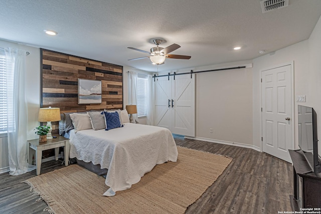 15166 Orpheus Way, San Antonio, TX 78245 - bedroom featuring a barn door, wood finished floors, wood walls, baseboards, and recessed lighting