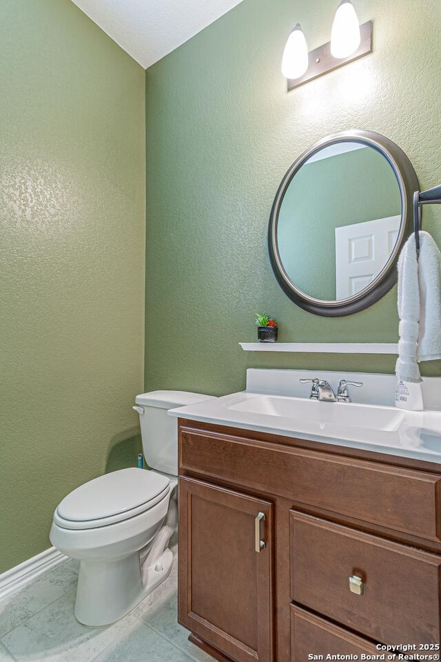 15166 Orpheus Way, San Antonio, TX 78245 - half bathroom with vanity, toilet, a textured wall, and baseboards